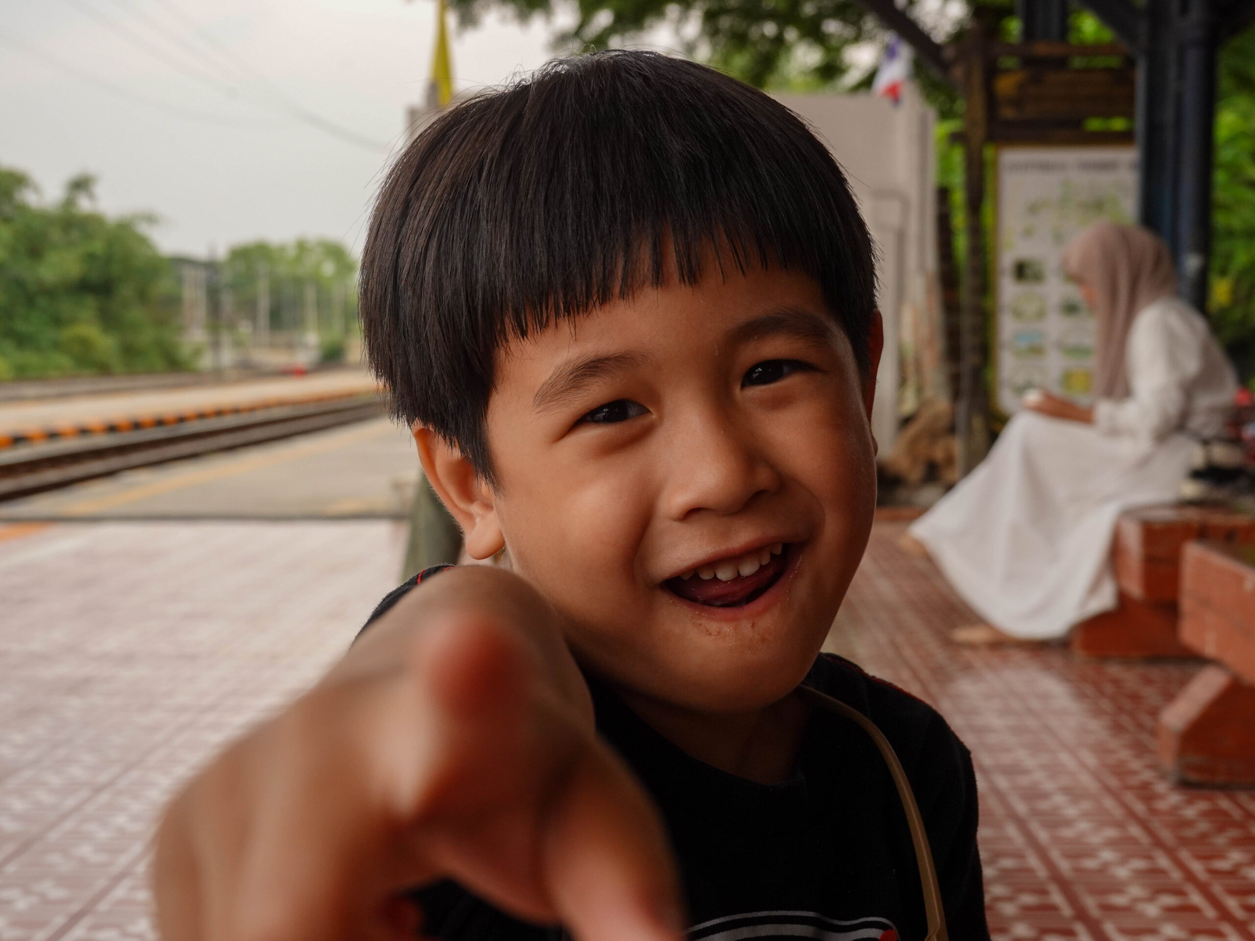 เด็กนั่งที่สถานีรถไฟ ชี้นิ้ว
