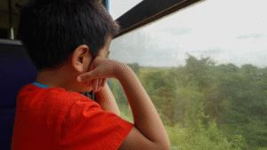kid on a train looking outside from window of a train